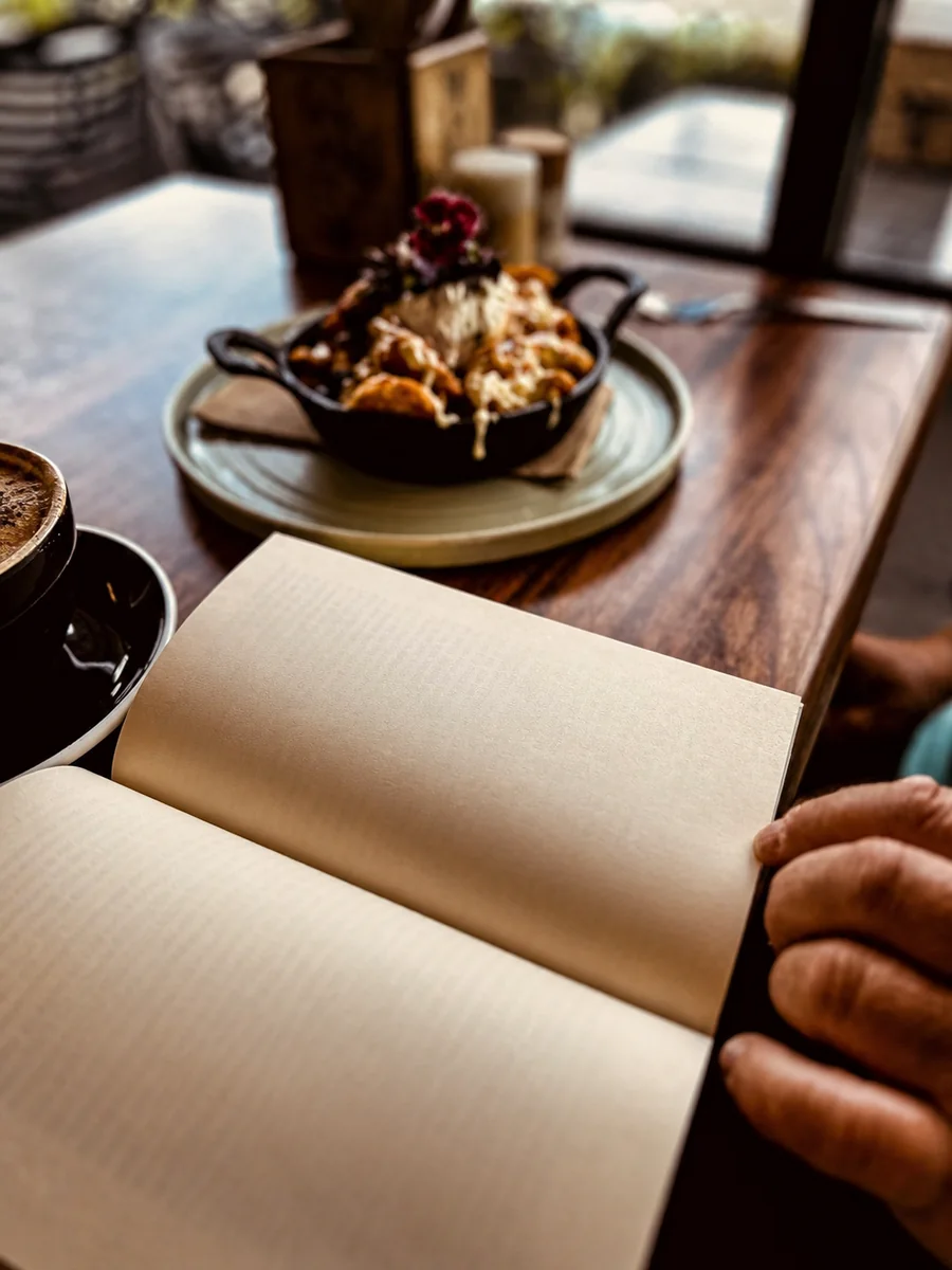 A guest reading beside food and coffee at Hey Jude Cafe